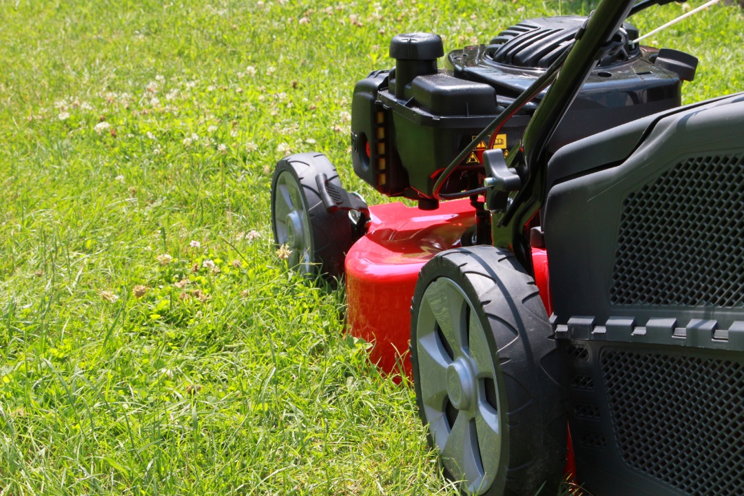 A side shot of a red push mower cutting grass.<br />
