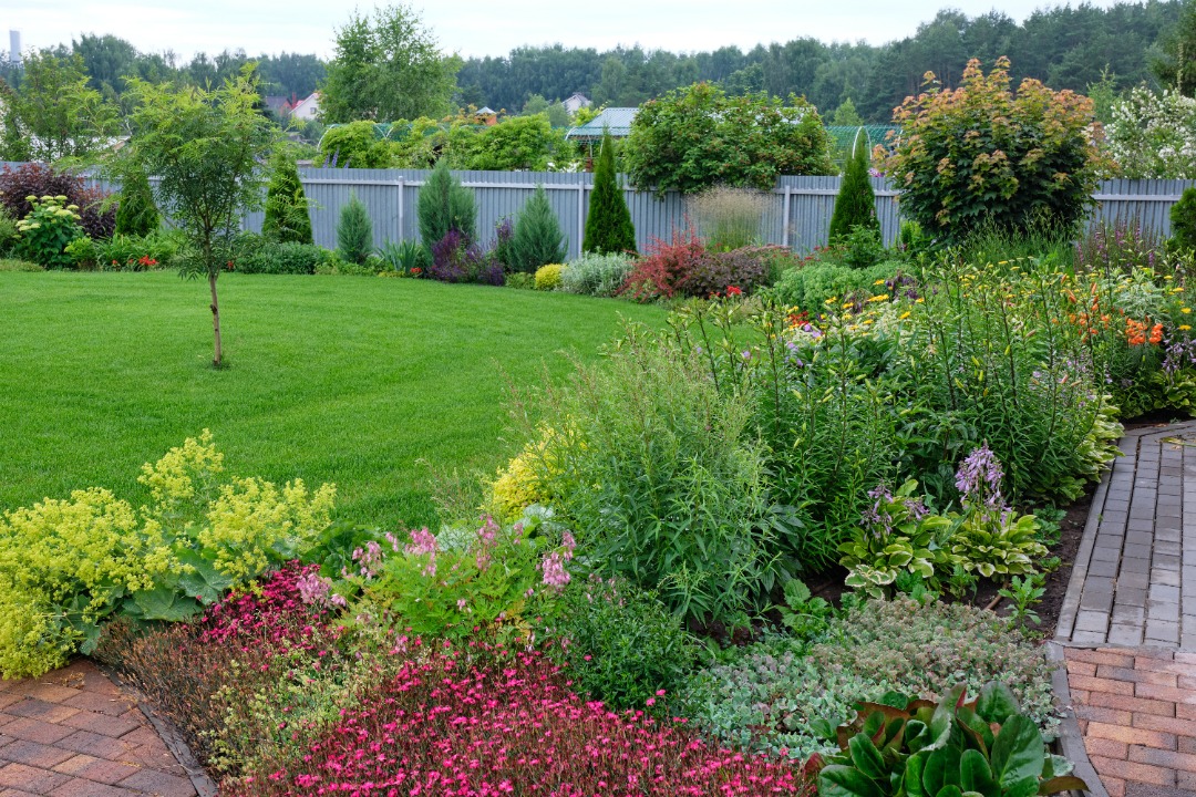 A lovely landscape with fresh cut grass and vibrant plants/flowers.